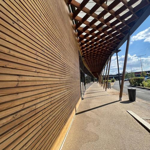 Allée ombragée par pergola en bois ajourée longeant bardage bois à Sainte-Eulalie